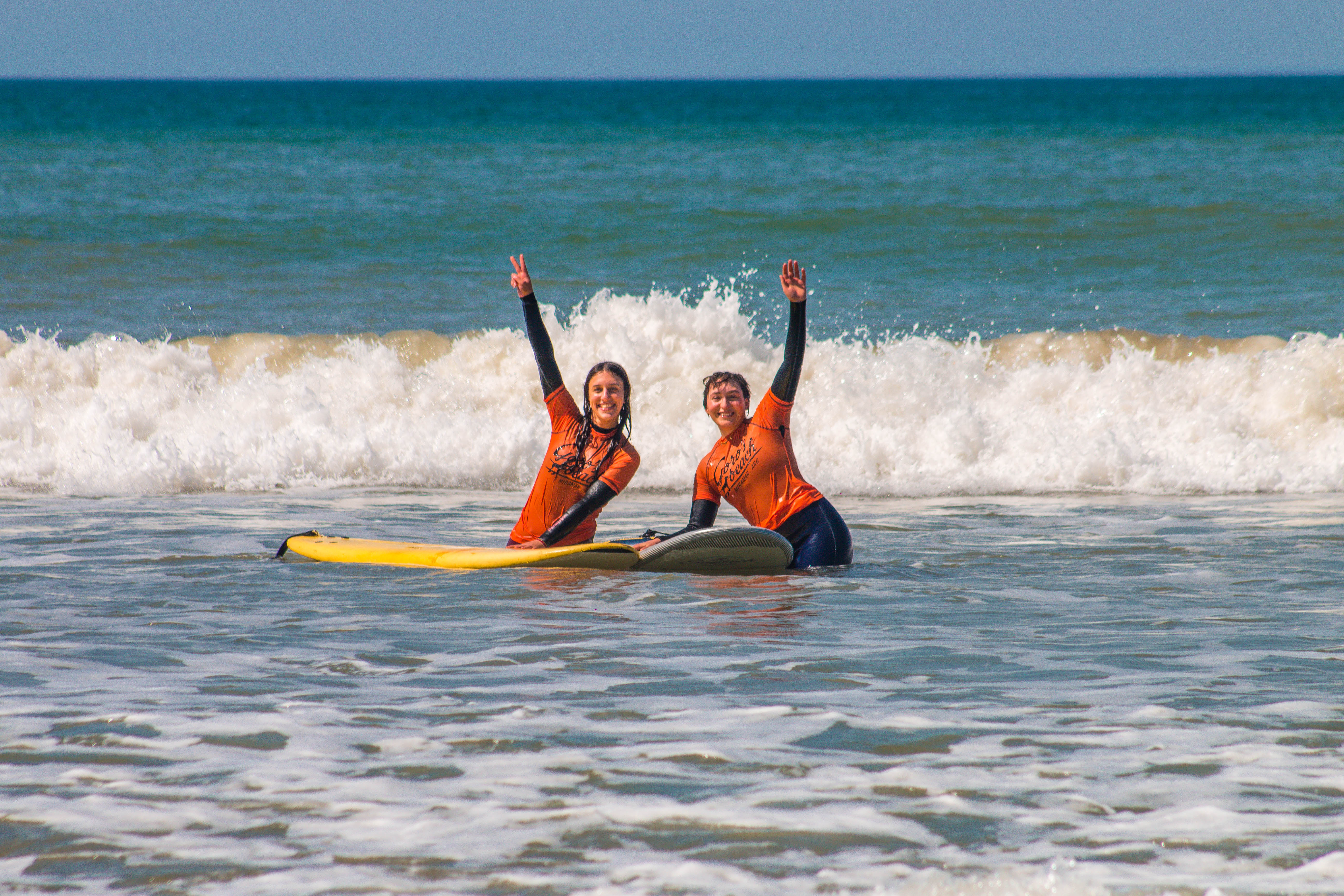 Dos chicas celebrando en el mar con sus tablas de surf